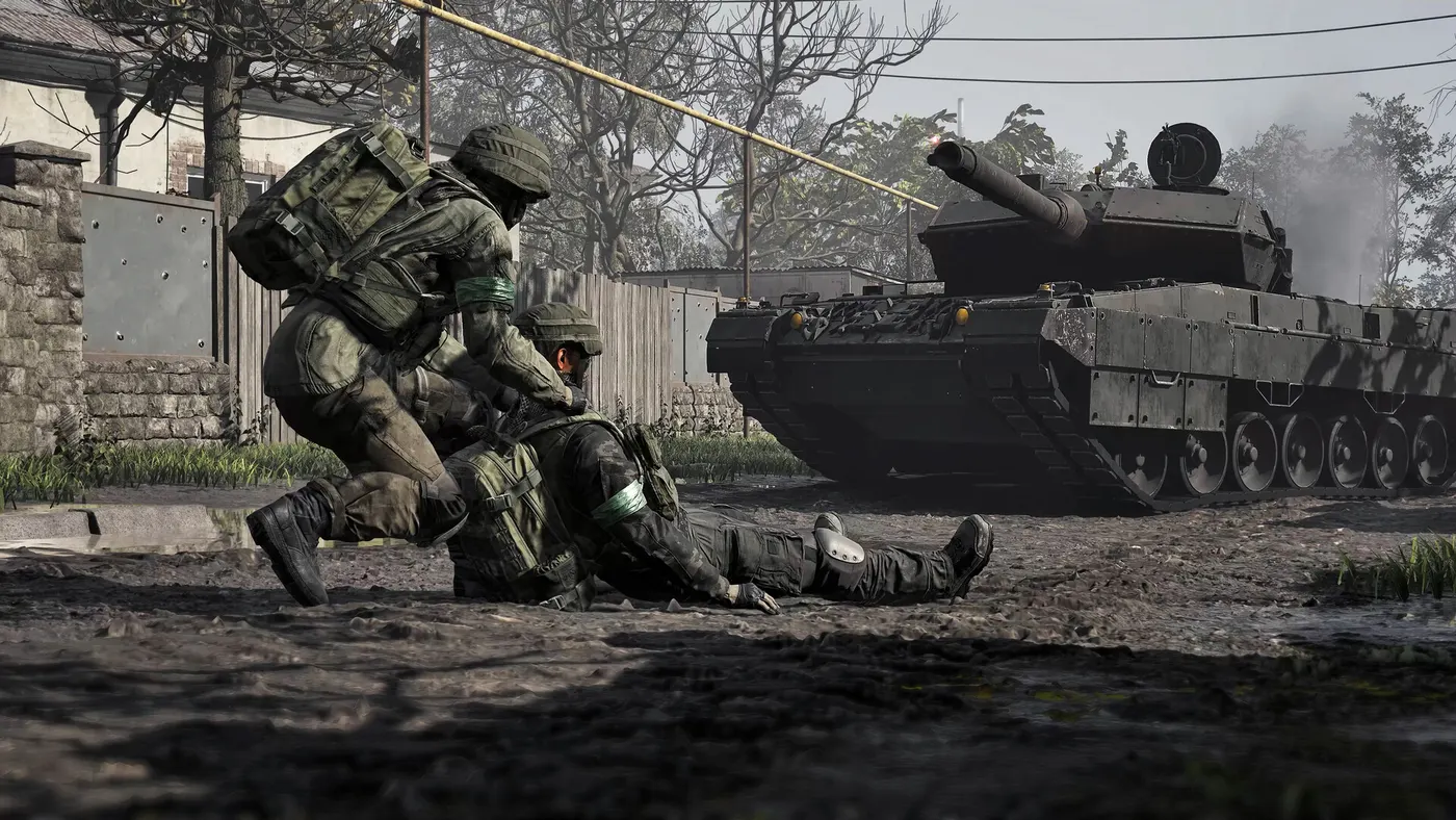 A medic drags a wounded comrade out of the line of fire, a battle tank behind them